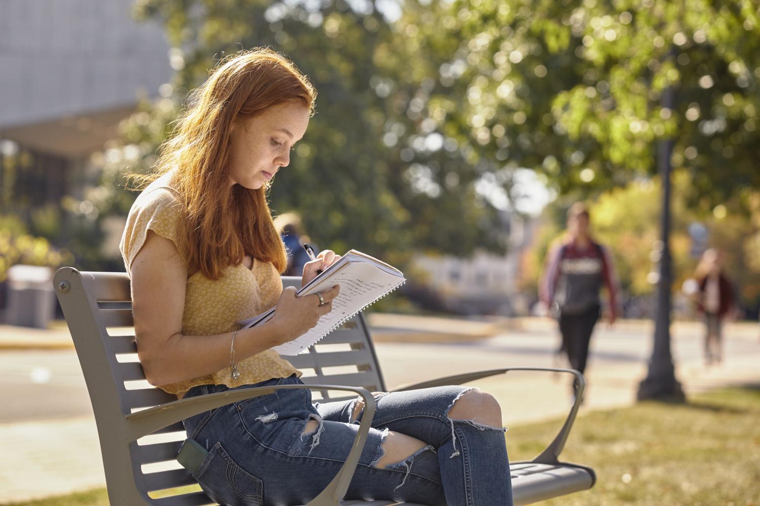 一位<a href='http://3mln.svztur.com'>bv伟德ios下载</a>学院的学生在校园里的长椅上读书.